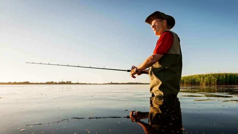 äldre man fiskar i sina bästa vadarbyxor